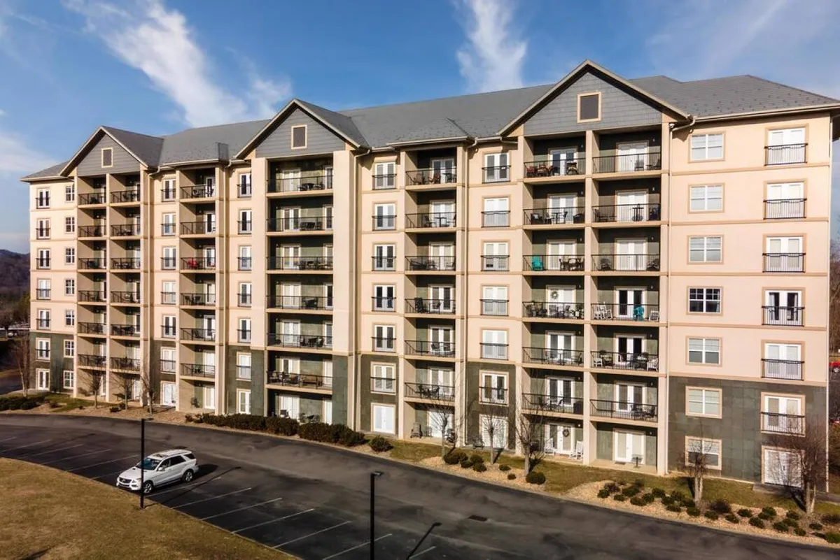 A multi-story resort building with multiple balconies and landscaped grounds, set in a welcoming, social environment. The golden-hour lighting hints at the perfect time for evening gatherings or enjoying the night sky.