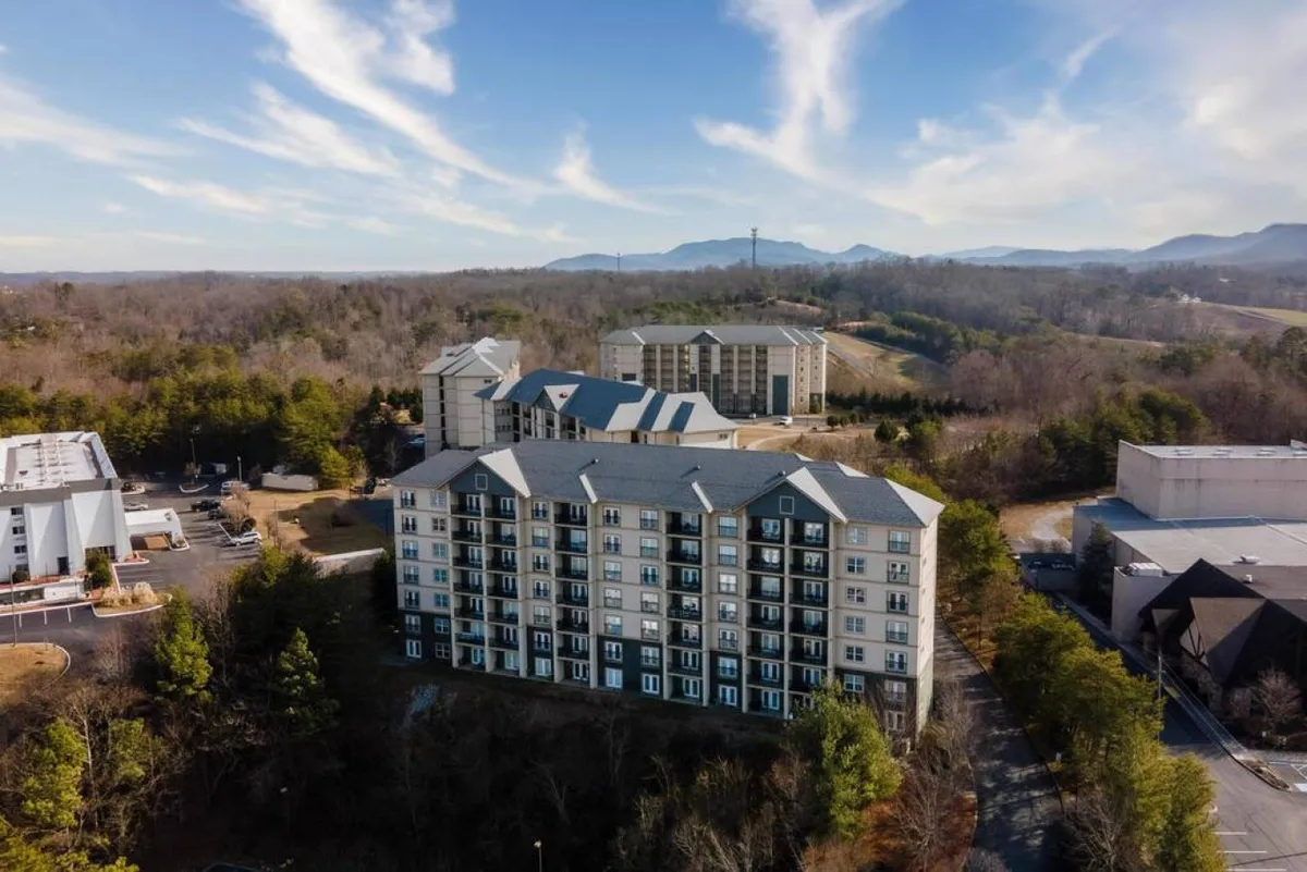 A welcoming view of a multi-story building with lush landscaped greenery and a dramatic mountain backdrop, this image conveys a sense of community, relaxation, and direct connection to nature. The inviting grounds suggest resort-level amenities and shared spaces ideal for group stays.