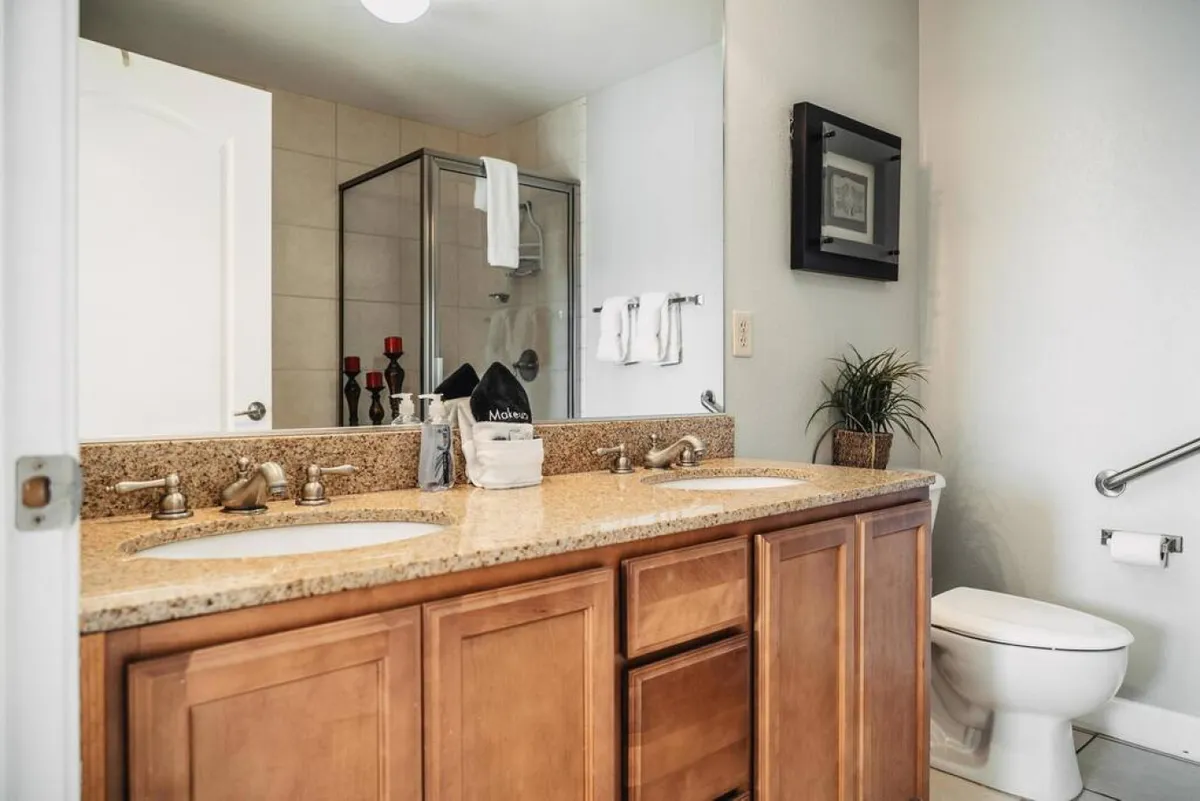 A modern, inviting bathroom with a double sink vanity, a glass shower enclosure, and decorative accents. The space feels bright, clean, and spa-like, ideal for morning or evening routines.